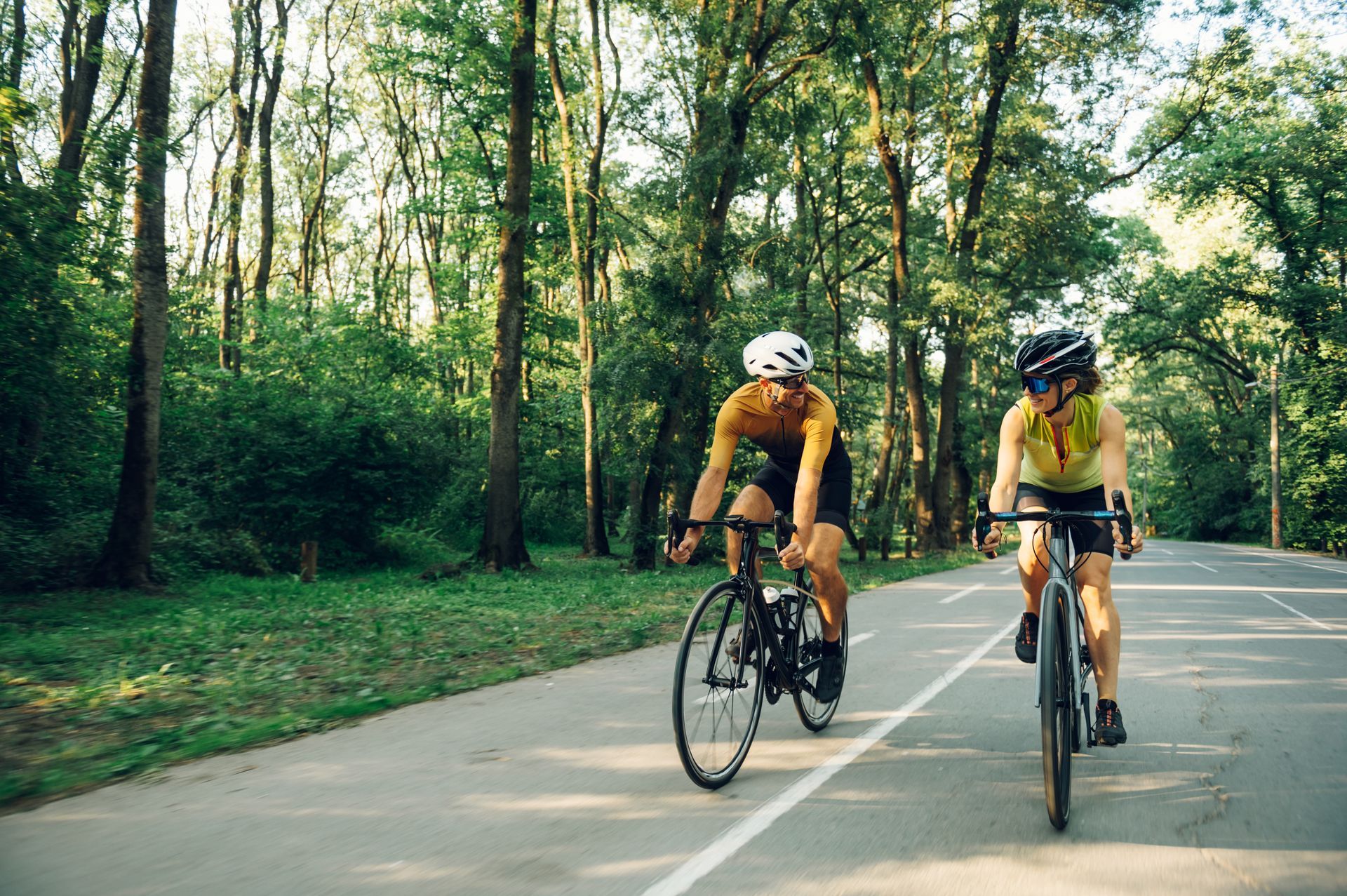 Two people are riding bicycles down a road.