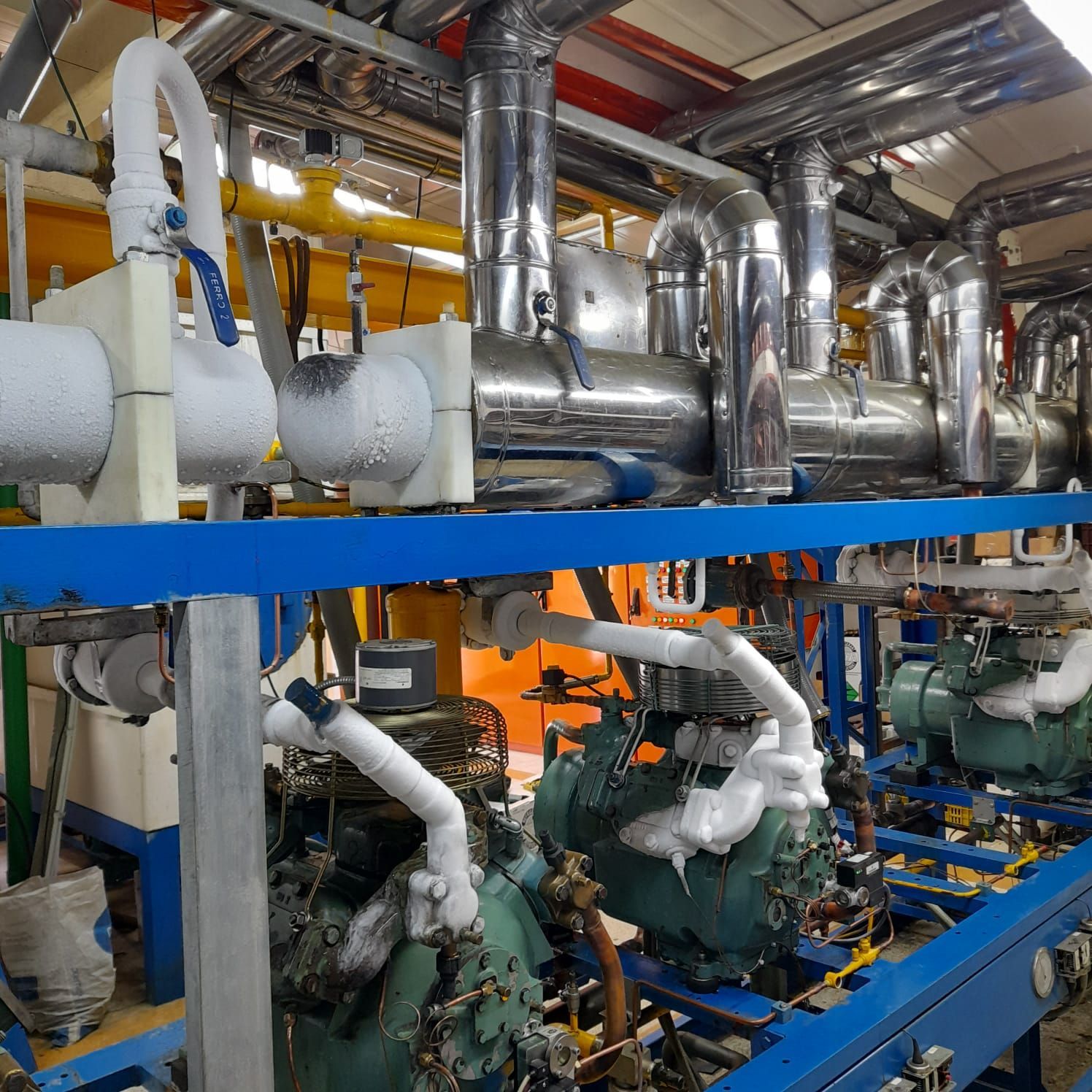 Equipos de refrigeración industrial con tuberías aisladas y compresores.