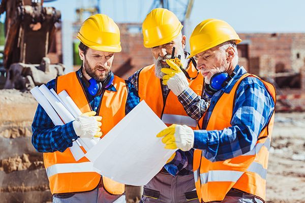 A construction worker is holding a hard hat and a tool belt.