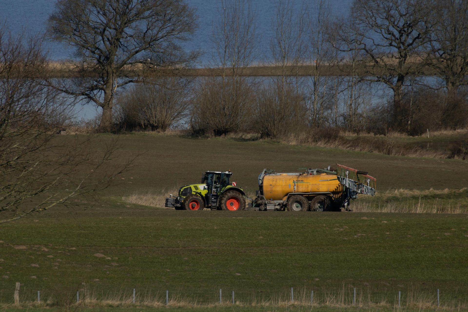 A tractor is plowing a field with a trailer attached to it.