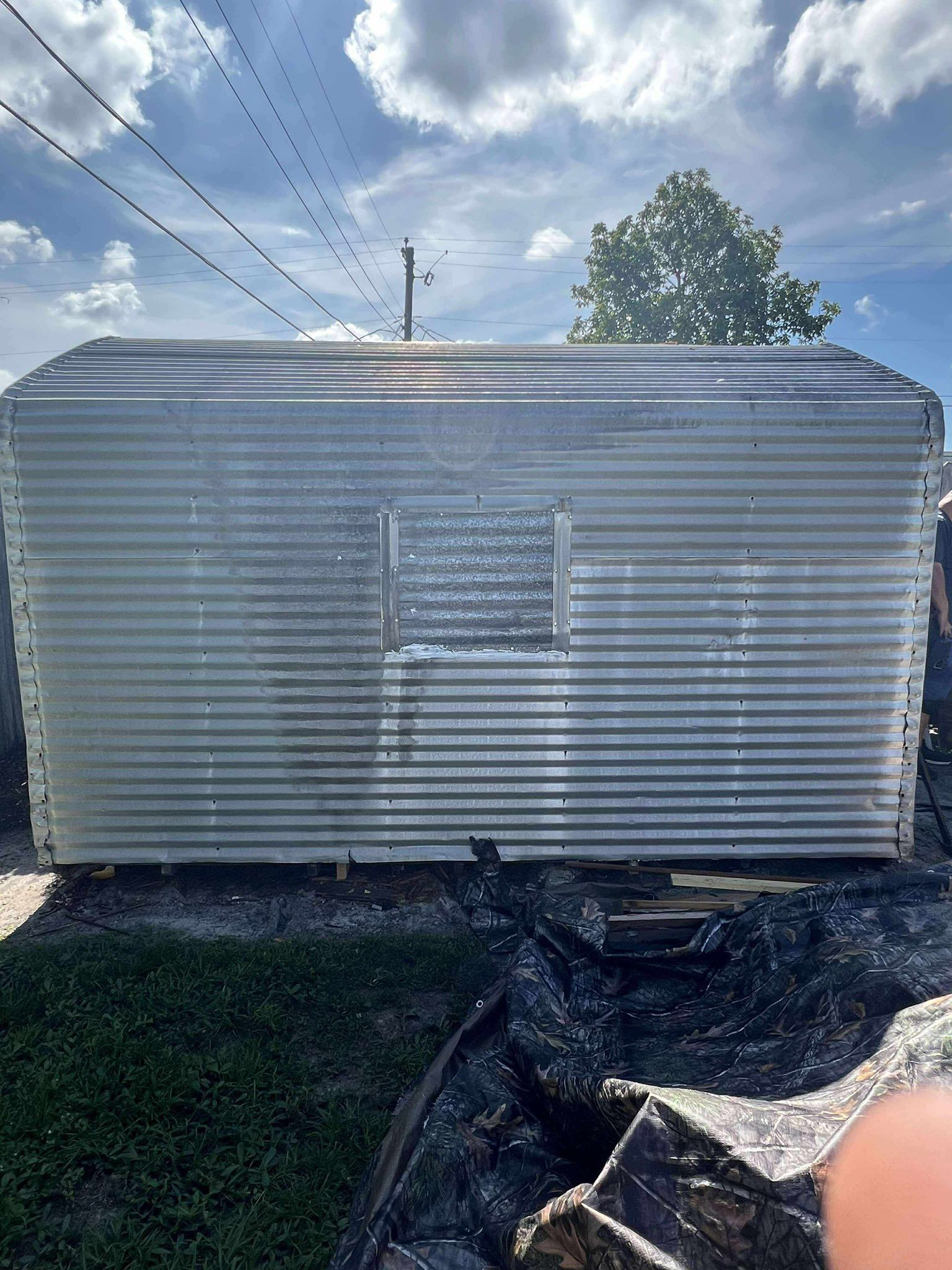 Galvanized metal shed with a window, outdoors on a cloudy day.