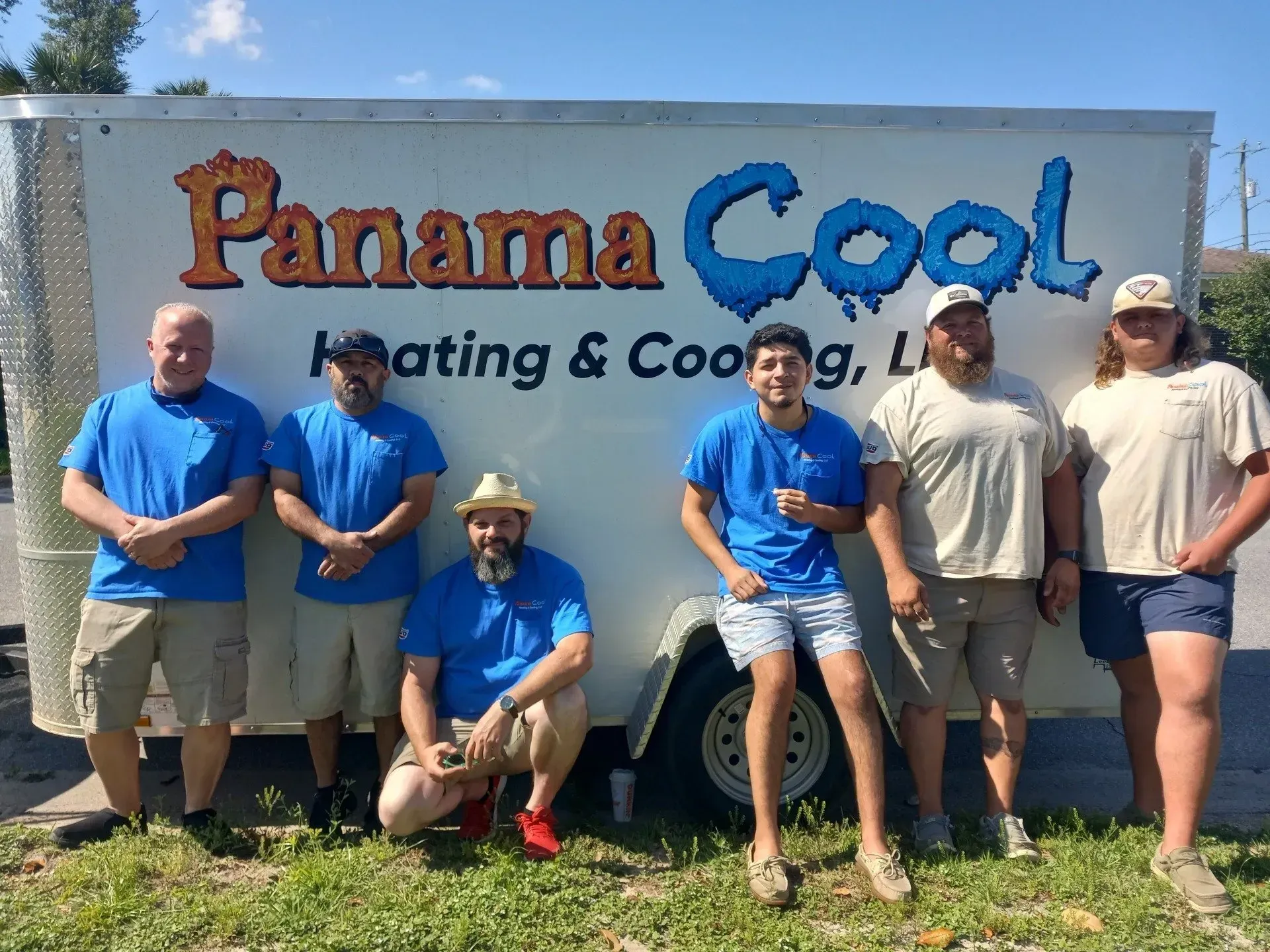 A group of men are posing for a picture in front of a panama cool trailer.