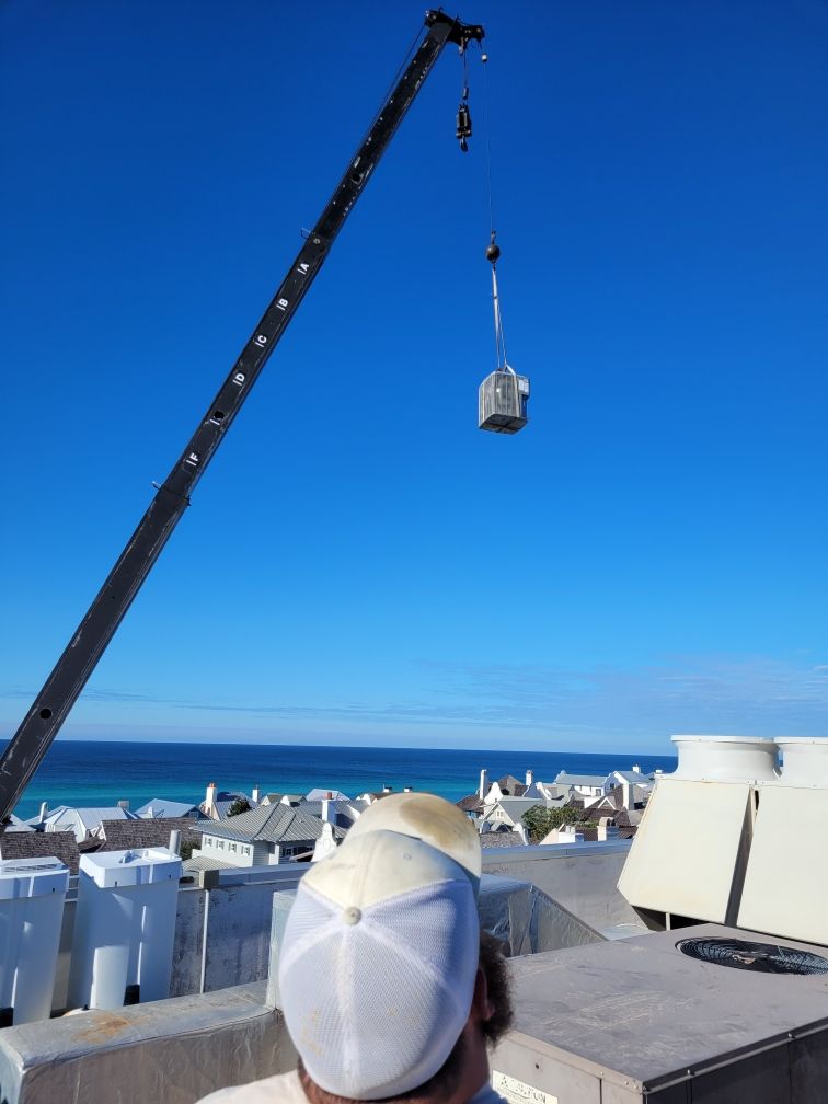 A man in a white hat is looking at a crane with a house hanging from it