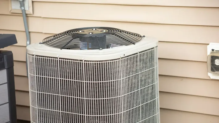 An air conditioner is sitting on the side of a house.
