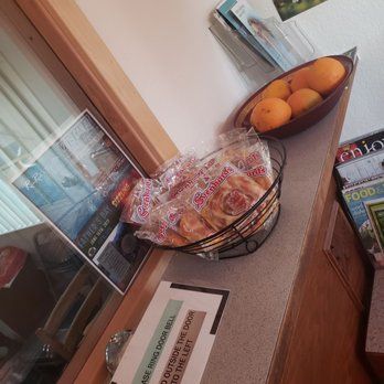 A bowl of oranges and a basket of pastries on a counter