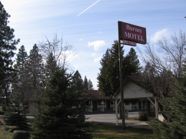 A burnes motel is surrounded by trees and grass