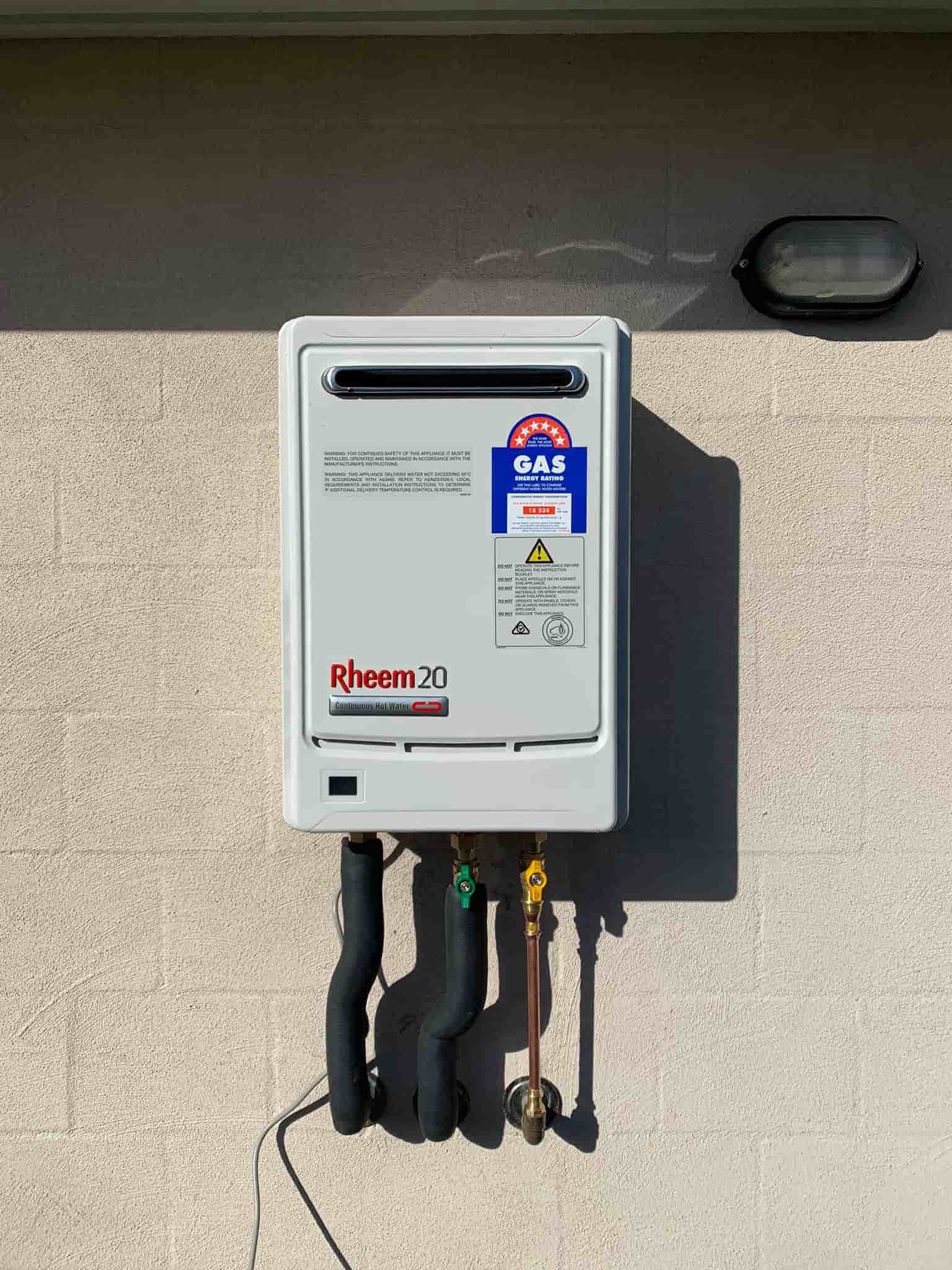 A White Water Heater Is Mounted On The Side Of A Building — McGill Plumbing & Gas In Beaconsfield, QLD