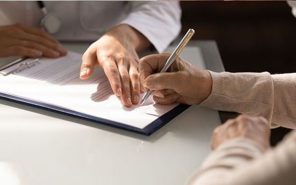 A doctor is talking to a patient who is signing a document.