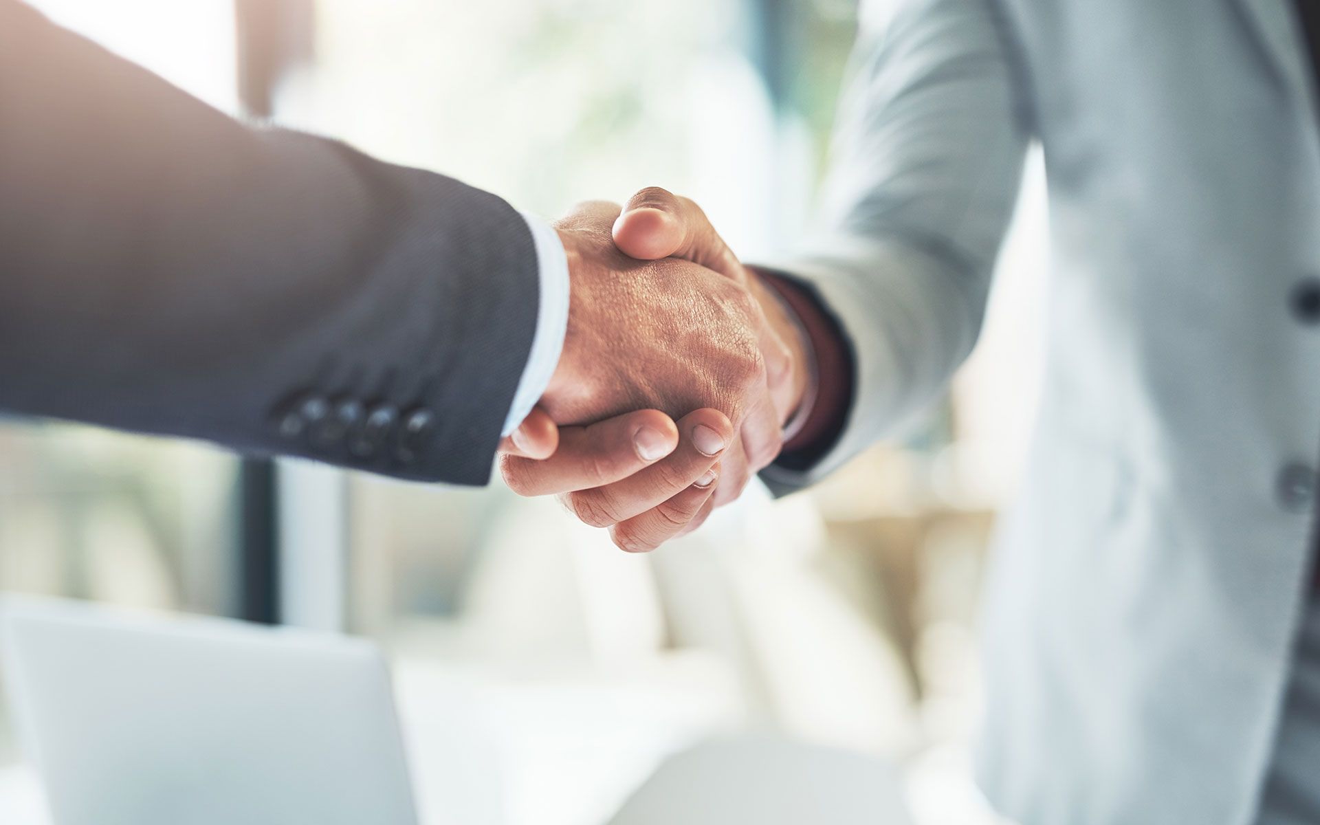 A man and a woman are shaking hands in an office.