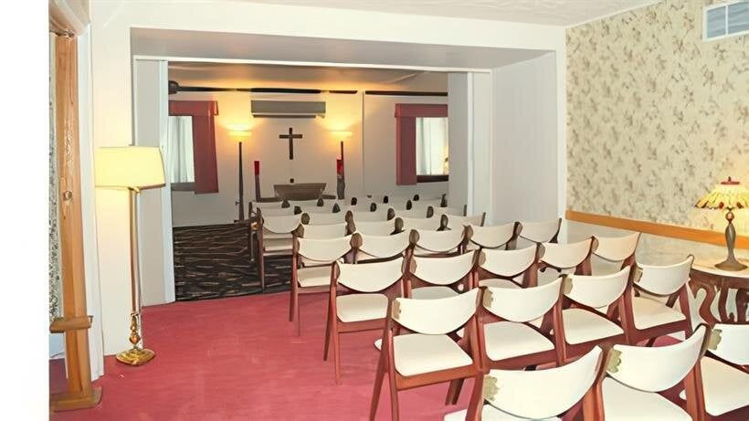 A room with rows of chairs and a cross on the wall