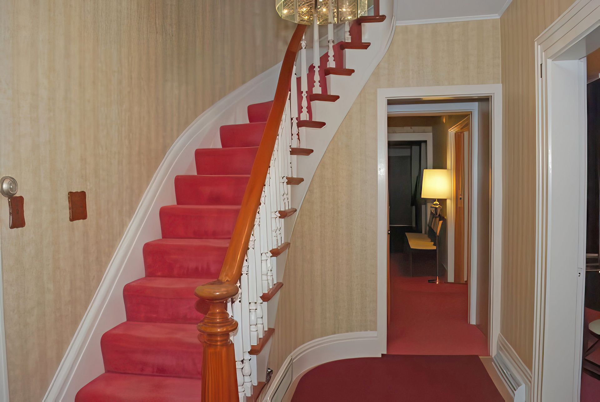 A staircase with red carpet and a white railing
