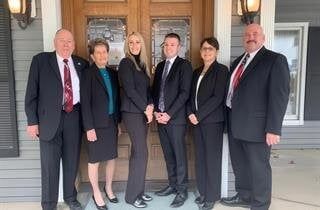 A group of people in suits and ties are standing in front of a door.