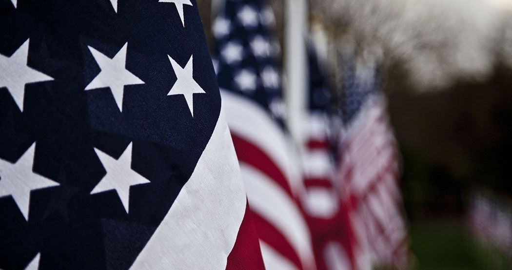 Several american flags are lined up in a row