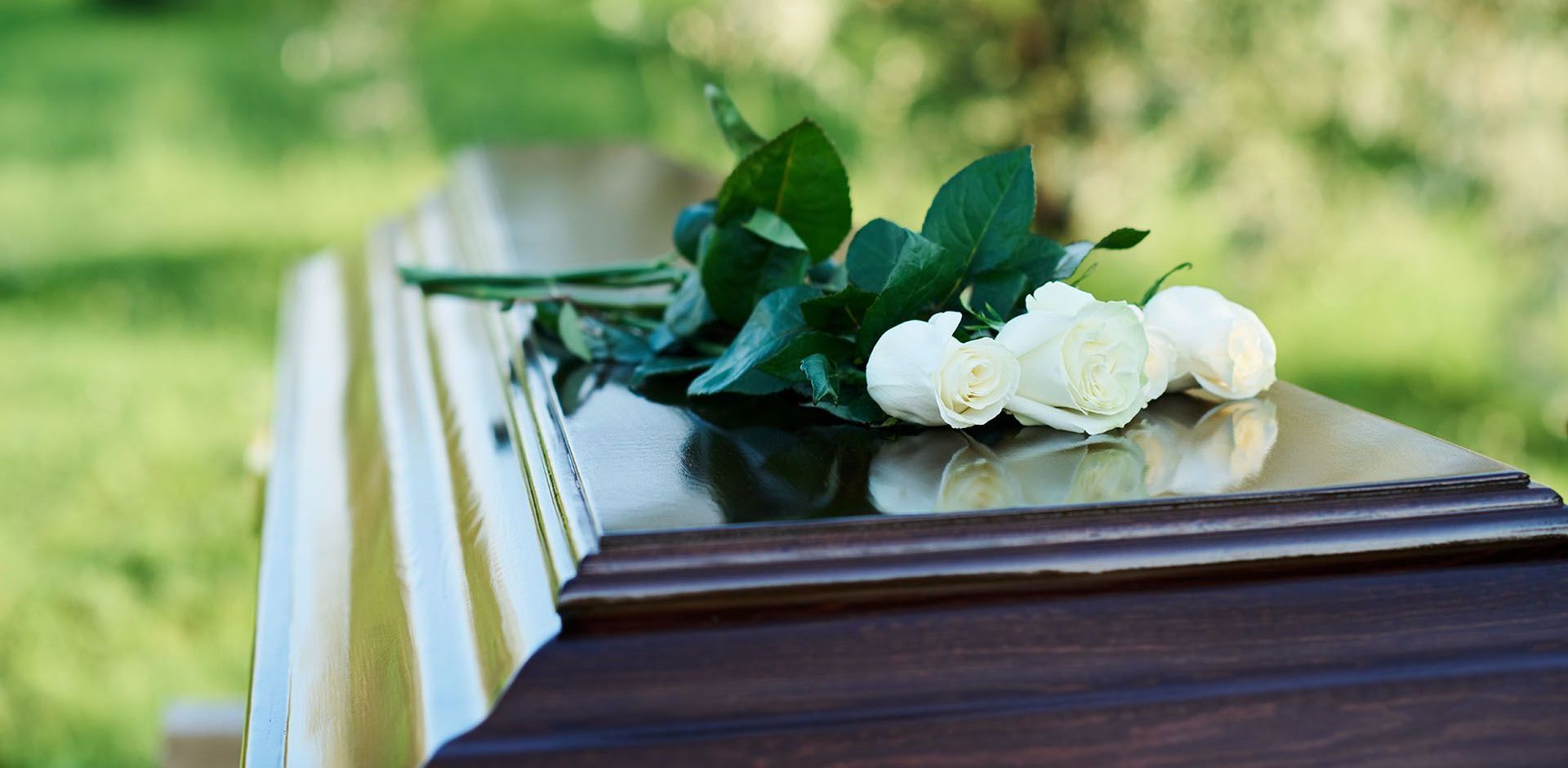 A wooden coffin with white roses on top of it.