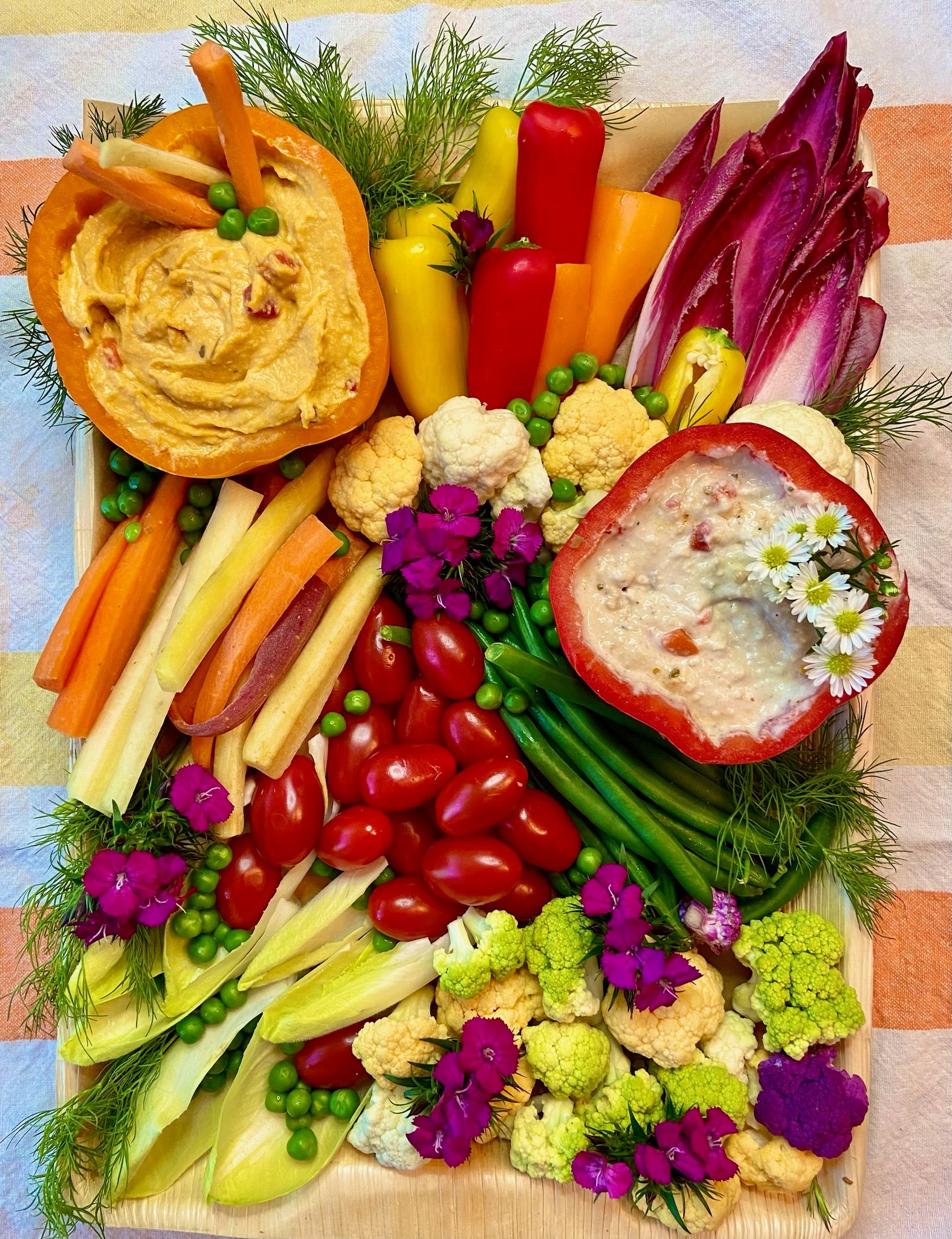 A tray of vegetables and hummus on a table.