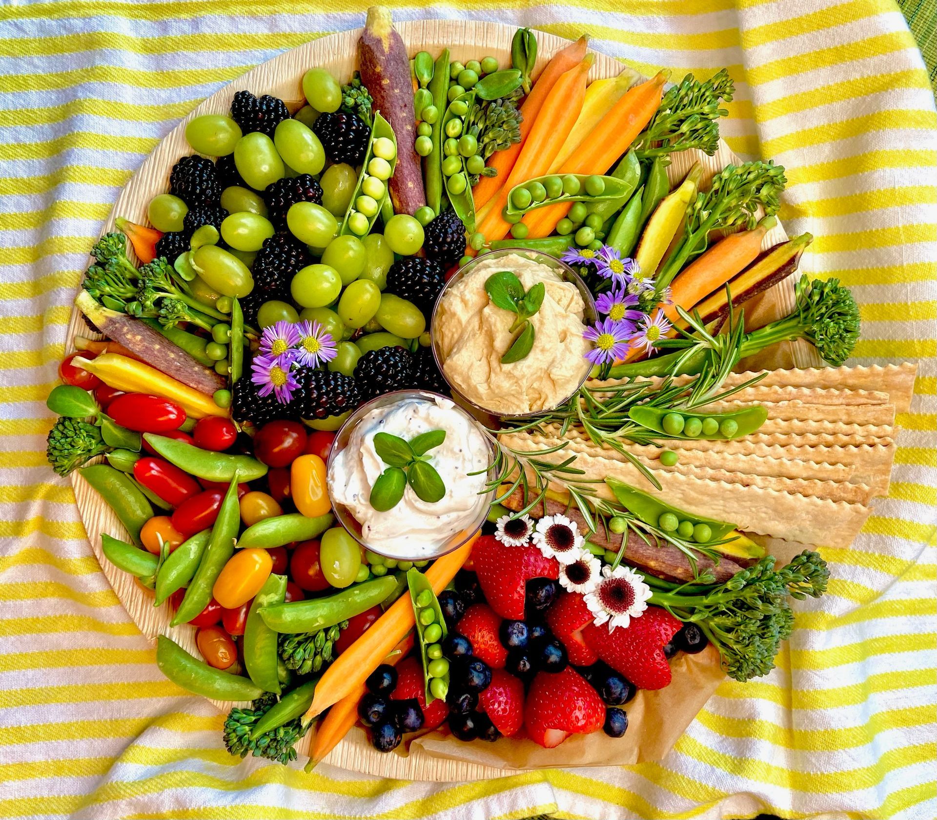 A plate of fruits and vegetables on a blanket on a table.