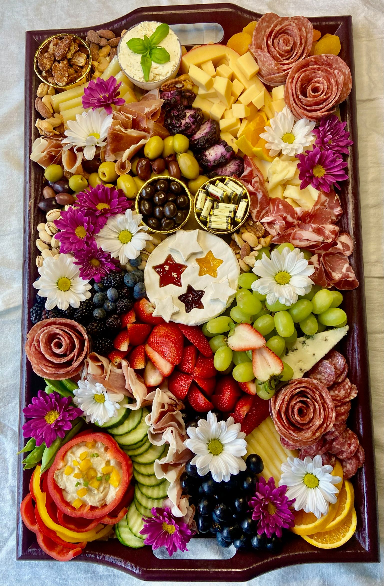 A tray filled with lots of different types of food and flowers.