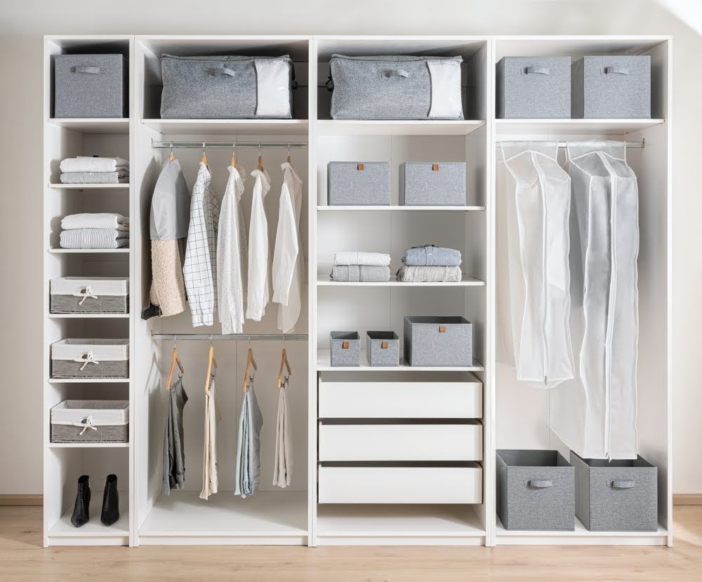 A large white wardrobe filled with clothes and drawers.