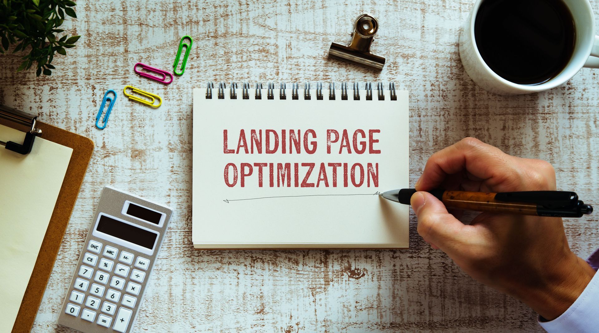 A person is writing on a notepad about landing page optimization.