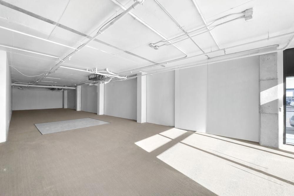 A large empty room with white walls and a tan carpet.