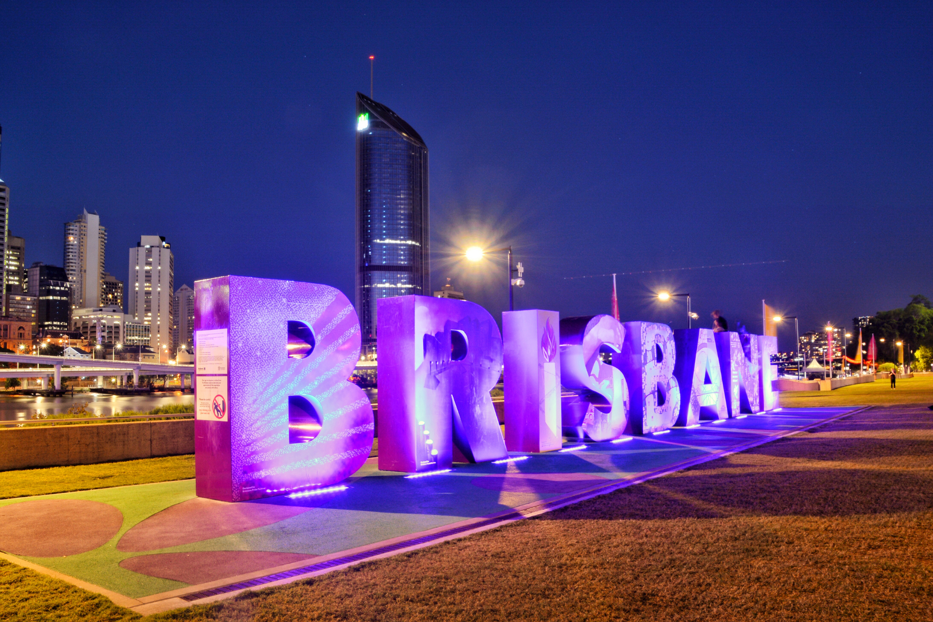 A sign that says brisbane is lit up at night