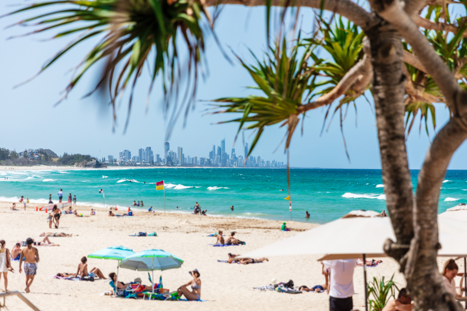 A beach with a lot of people on it and a city in the background.