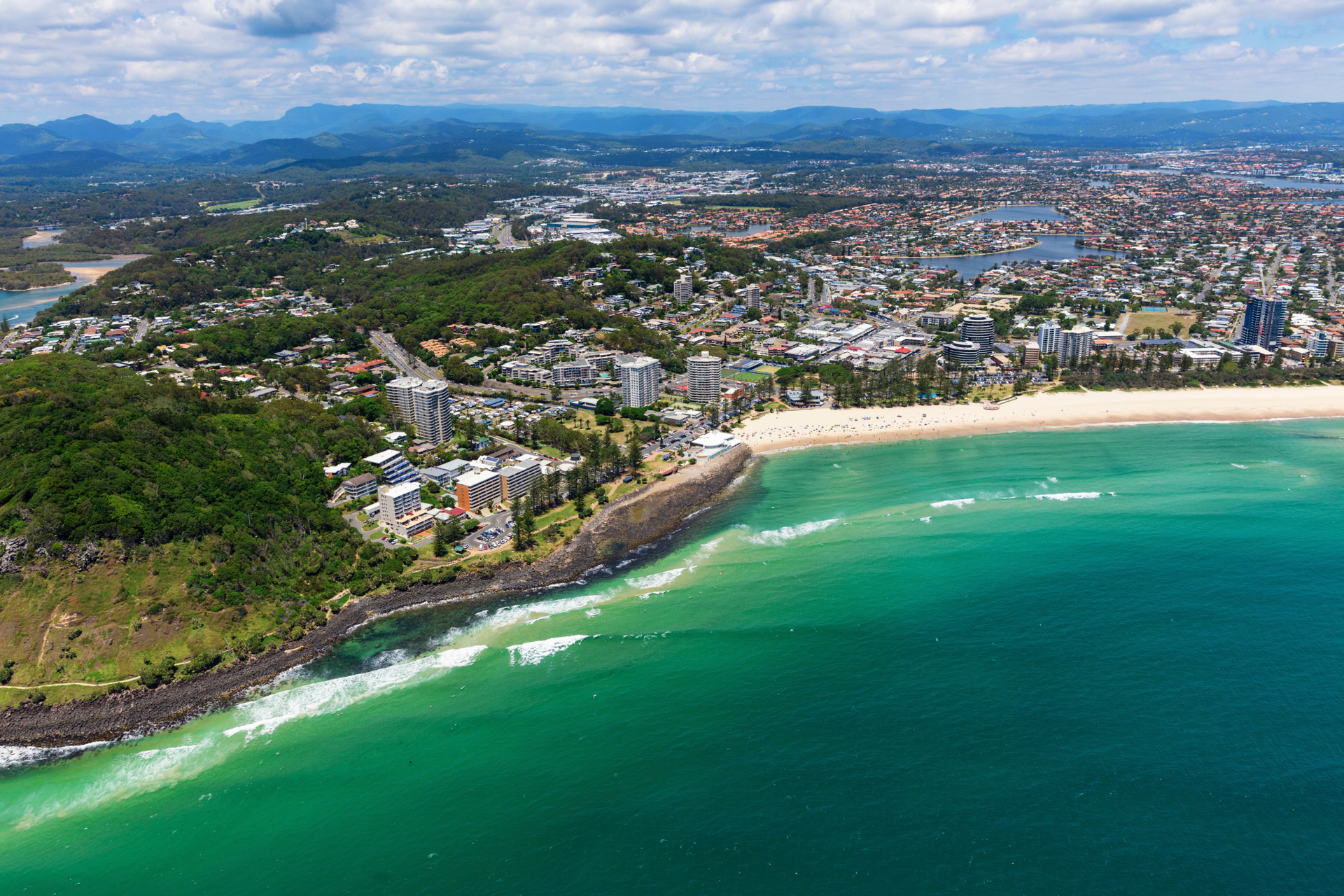 An aerial view of a beach with a city in the background.