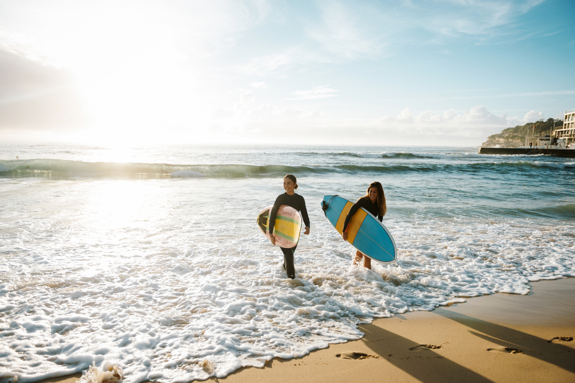 Two surfers are walking out of the ocean with their surfboards.