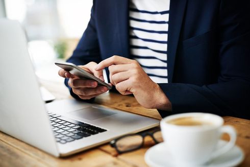 A man is sitting at a desk with a laptop and a tablet.