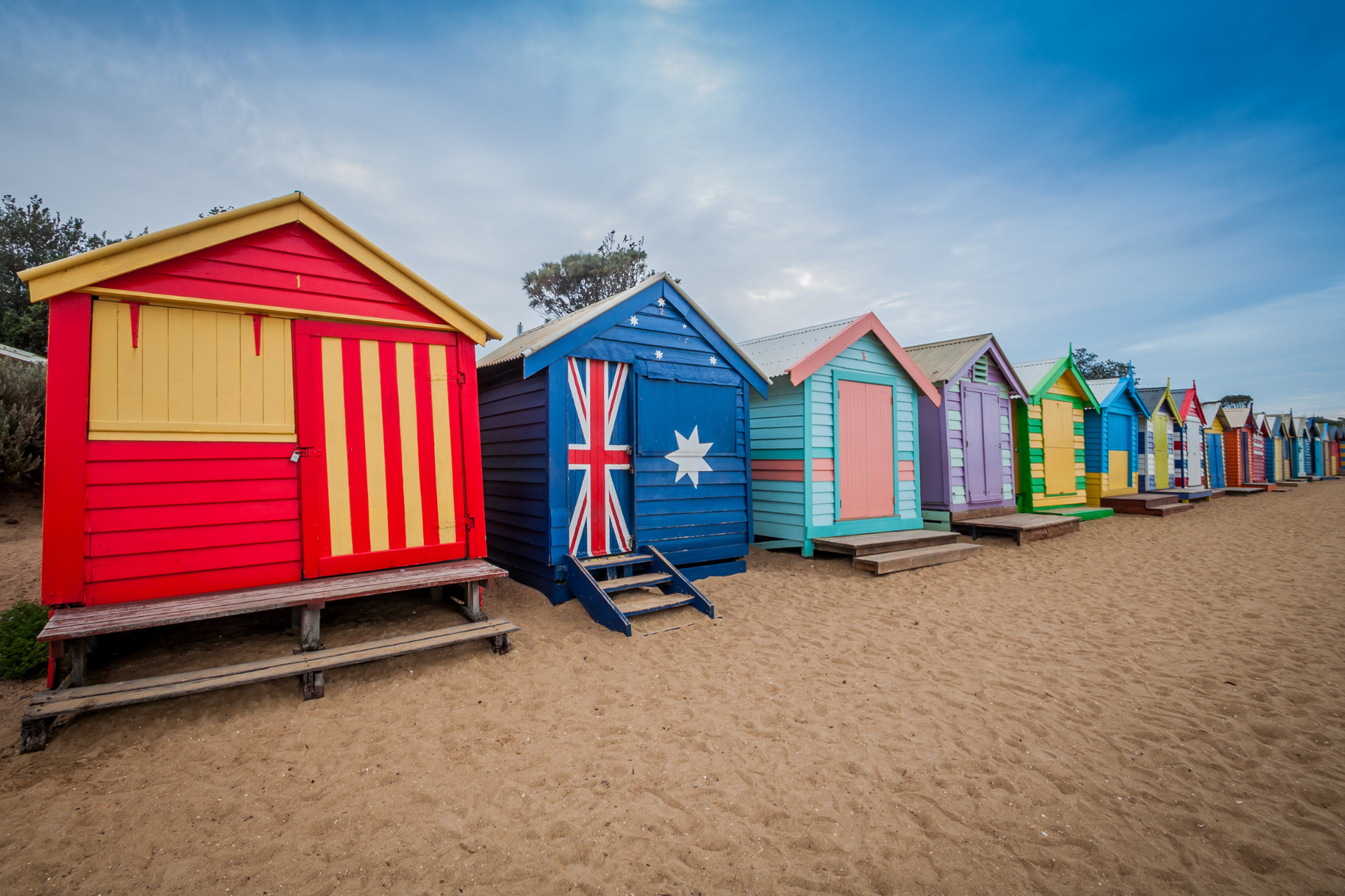 A row of colorful beach huts on a sandy beach.