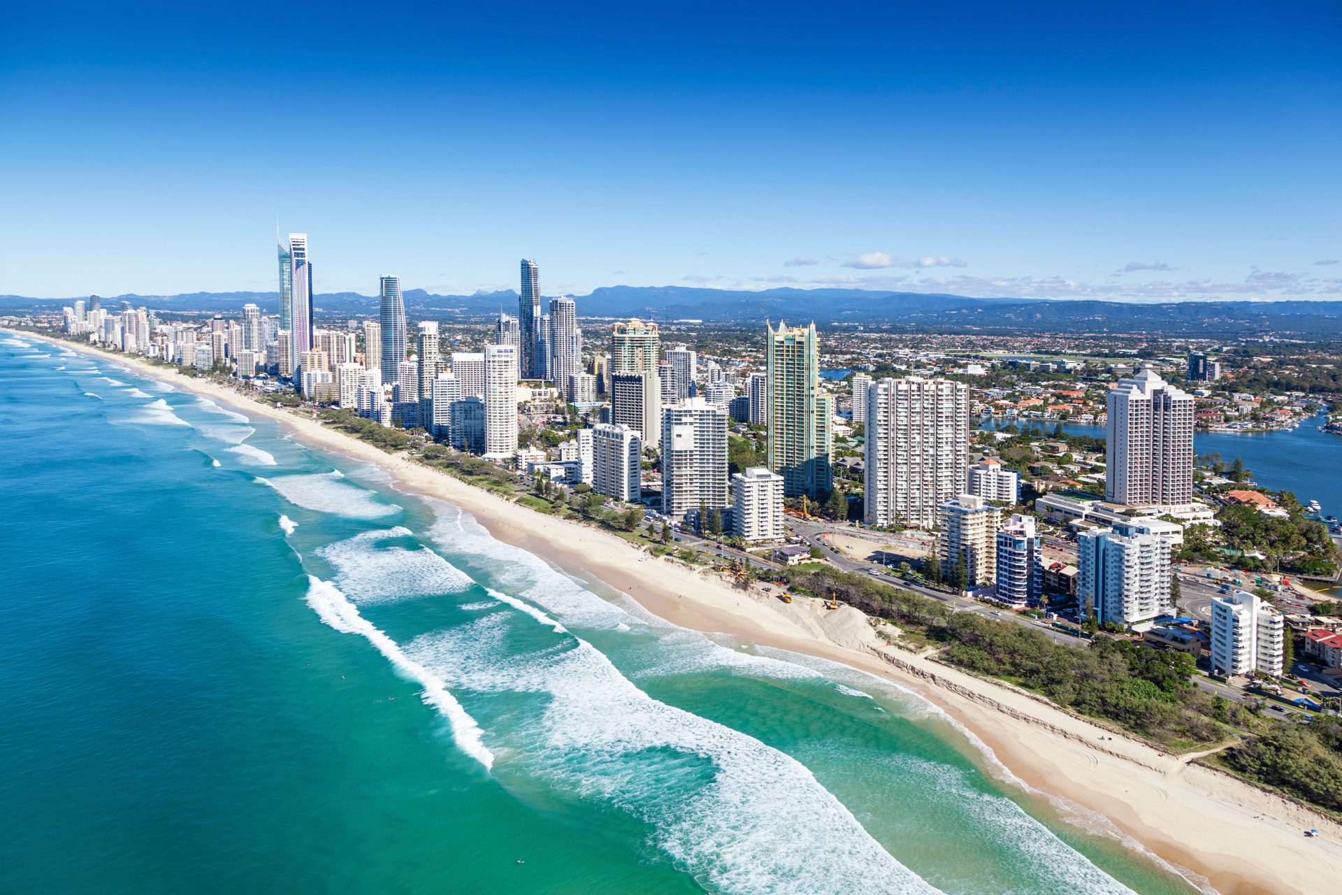 An aerial view of a city and a beach with waves crashing on the shore.
