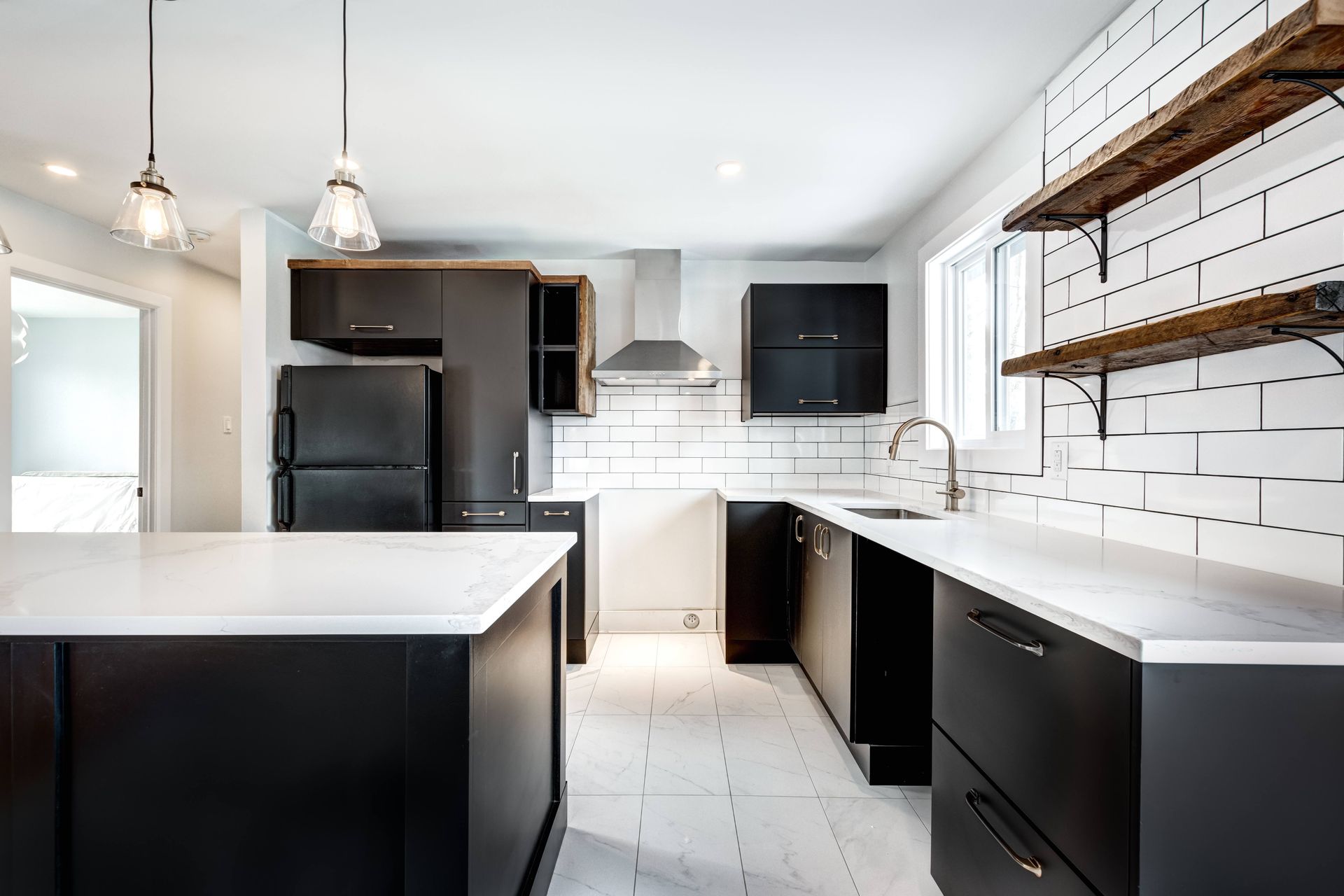 a kitchen with black cabinets , white counter tops , and a black refrigerator