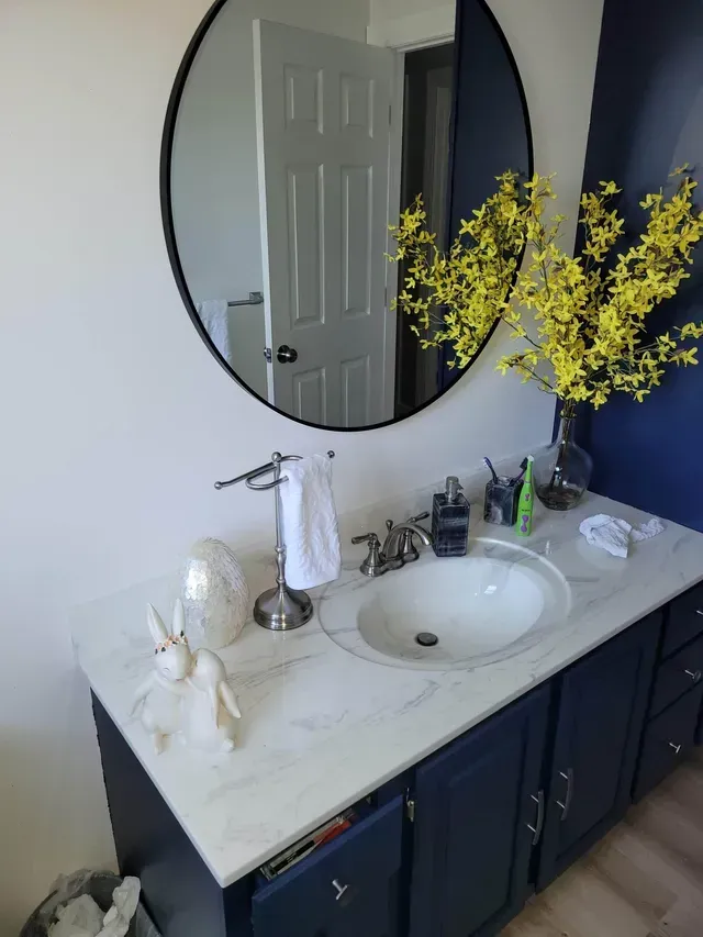 a bathroom vanity with a sink and a round mirror