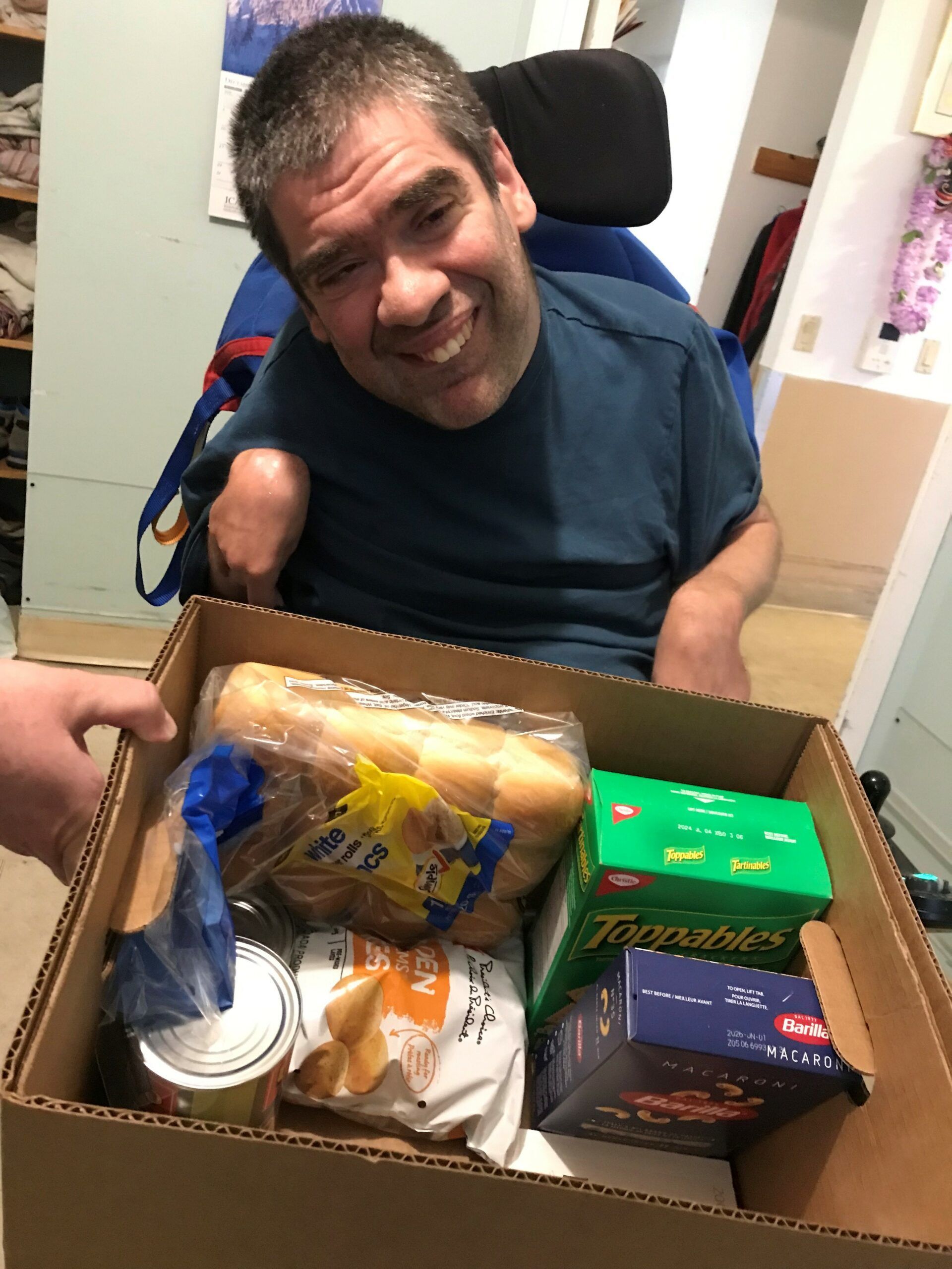 A man in a wheelchair is holding a box of food.