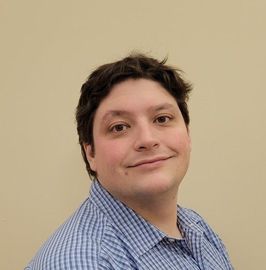 A man in a blue shirt is smiling for the camera