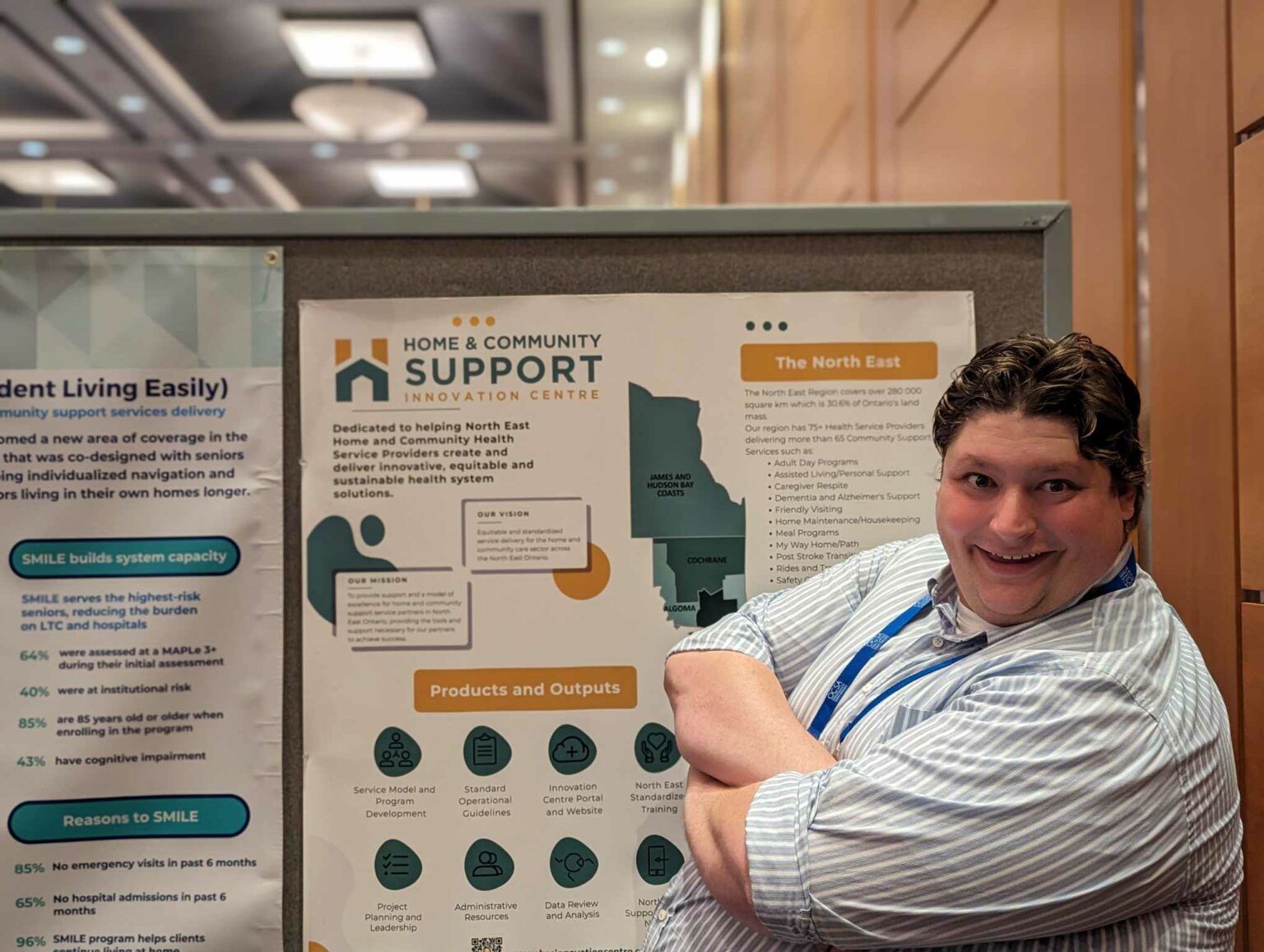 A man is standing in front of a Home and Community Support poster