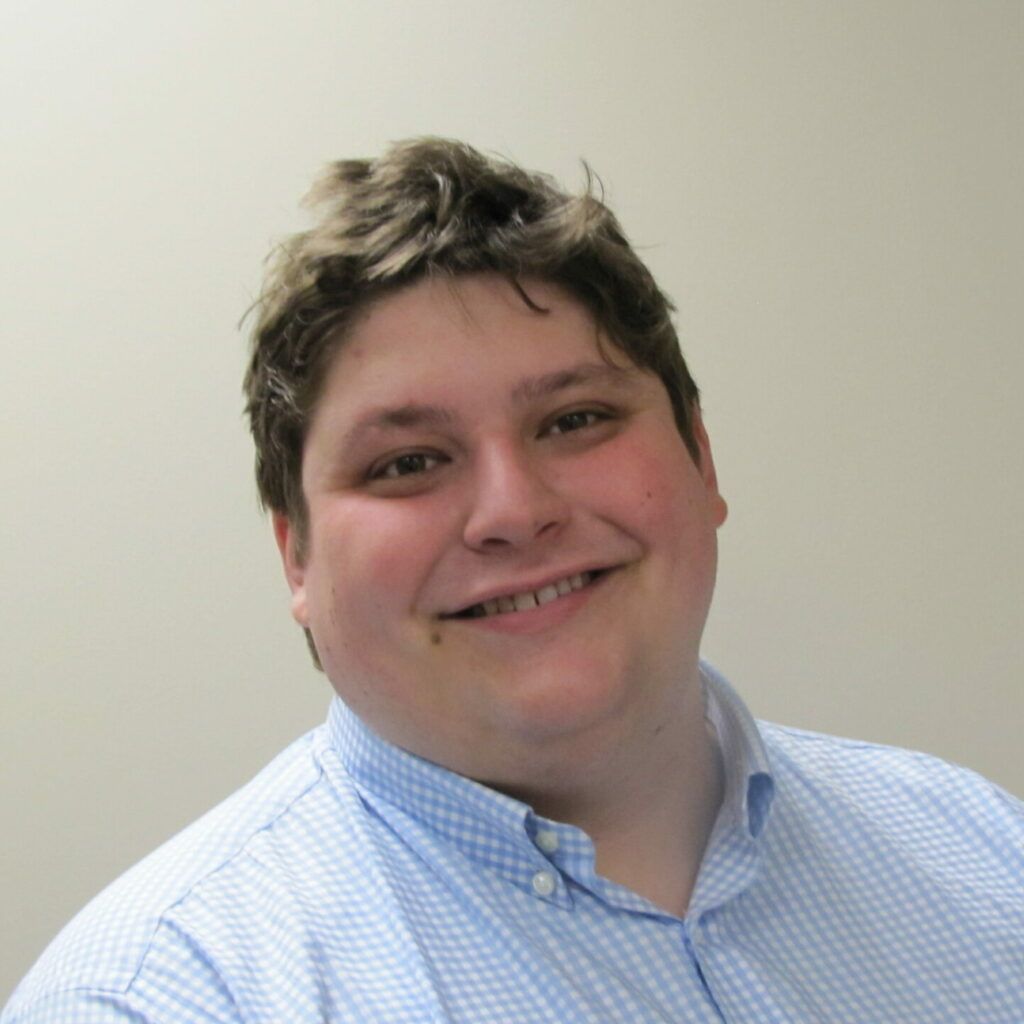 A man in a blue shirt is smiling for the camera