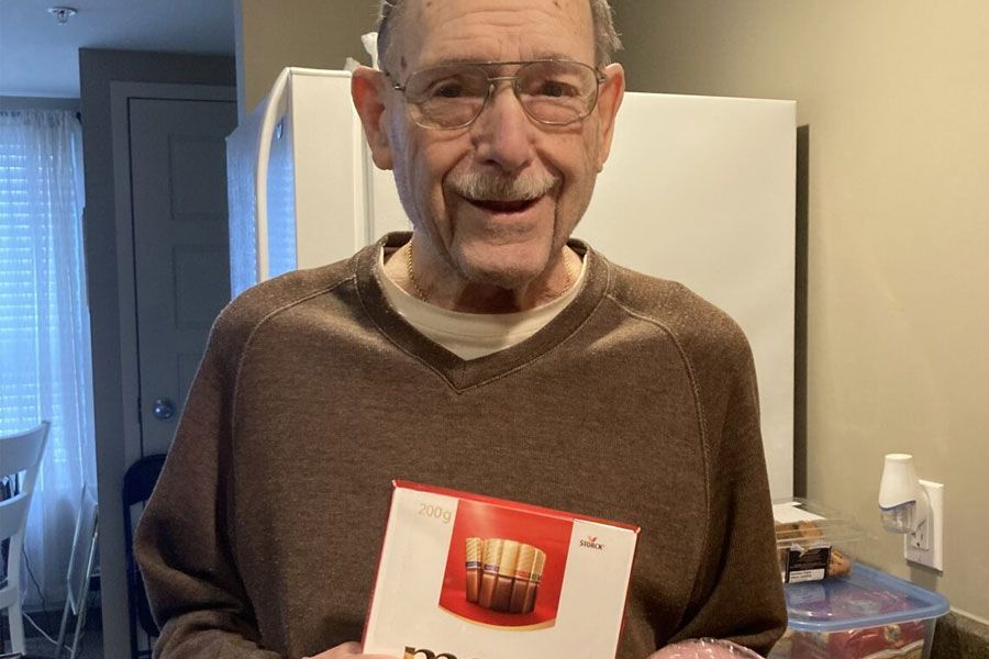 An elderly man is holding a box of popcorn in his hands.