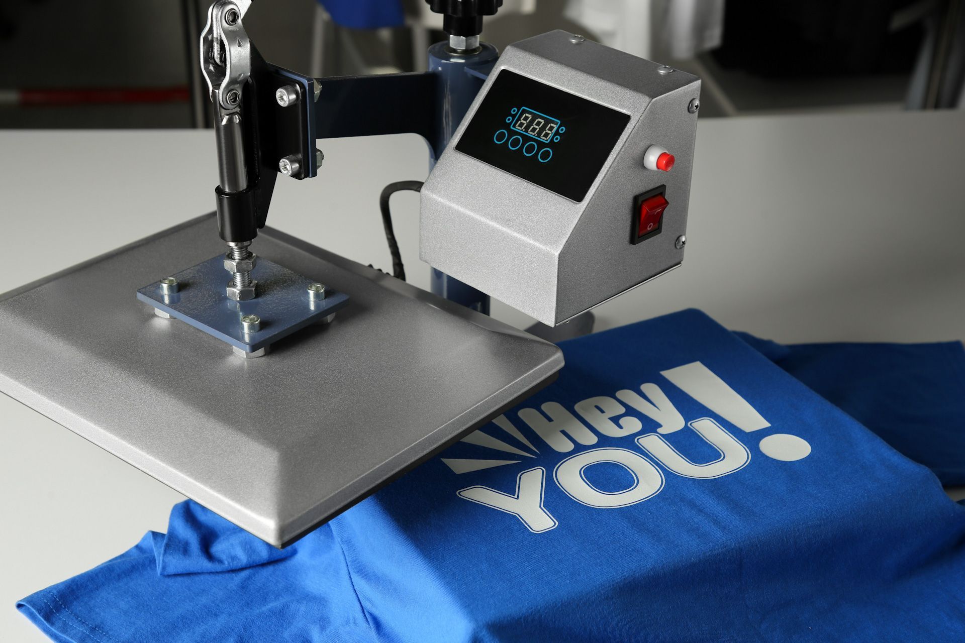 A machine is printing a blue shirt that says hey you on it.