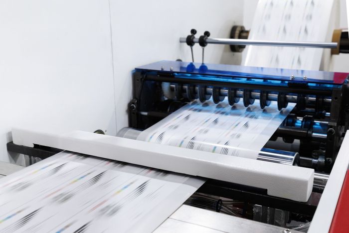 A machine is printing sheets of paper on a table.