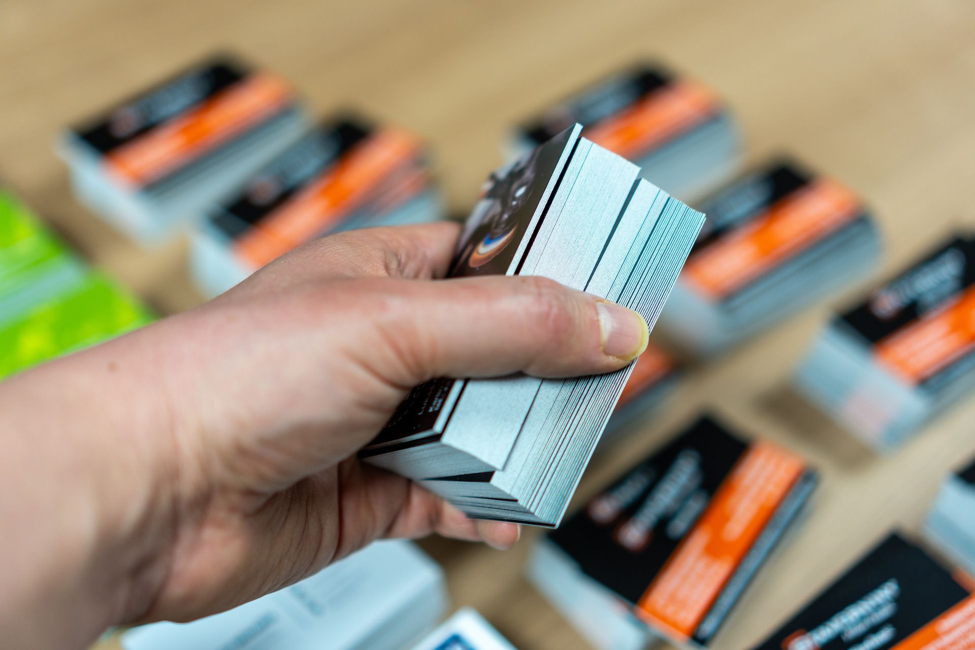 A person is holding a stack of business cards in their hand.