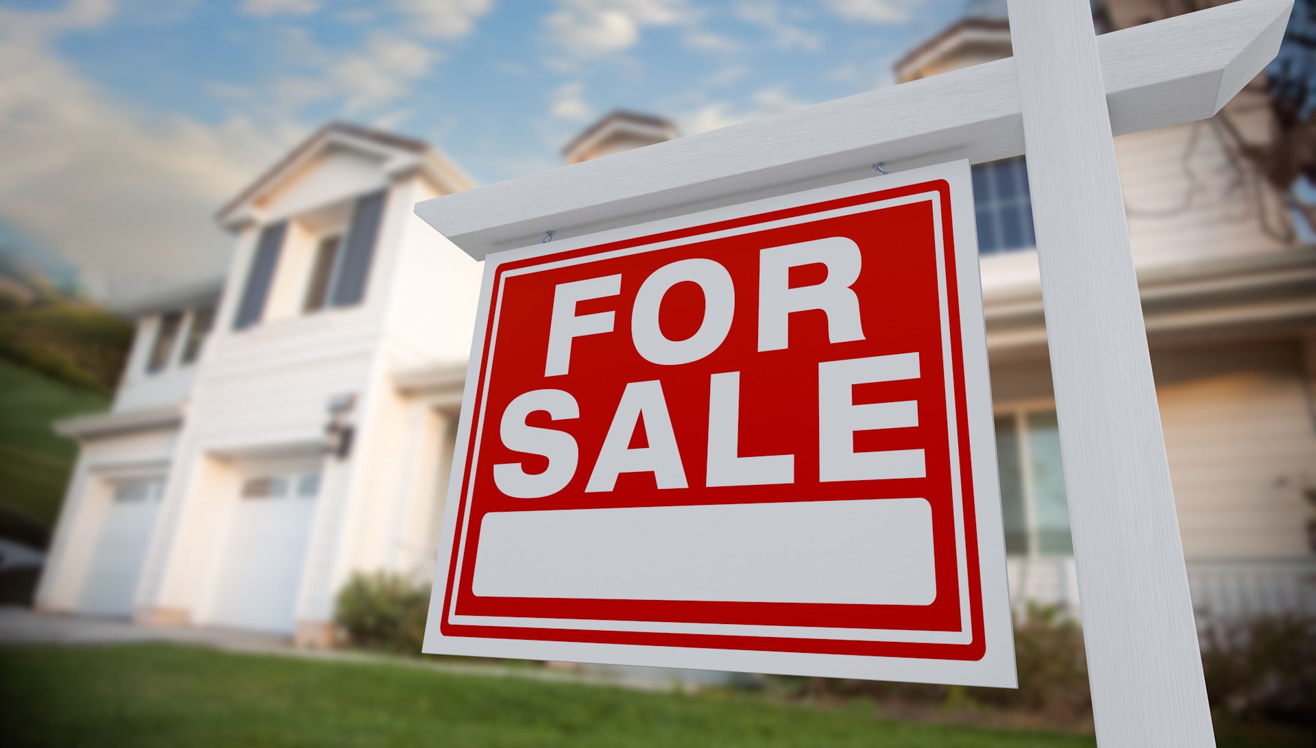 A for sale sign is in front of a house.