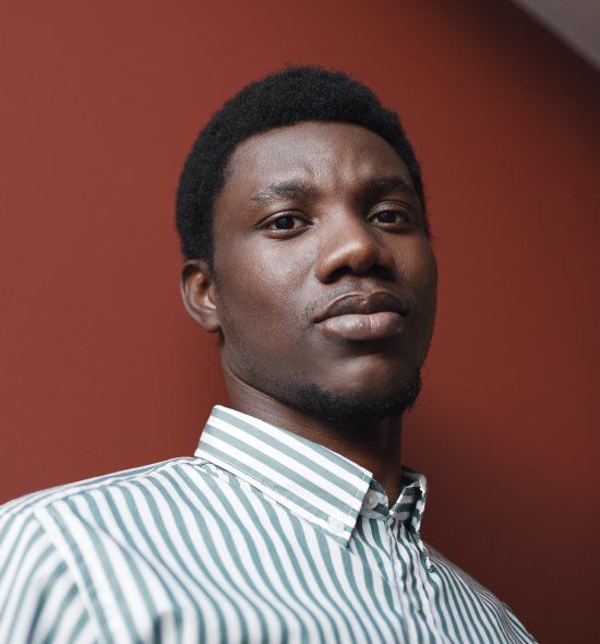 A man wearing a green and white striped shirt is looking at the camera.