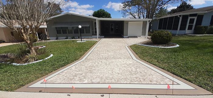 A driveway leading to a mobile home with a concrete walkway.