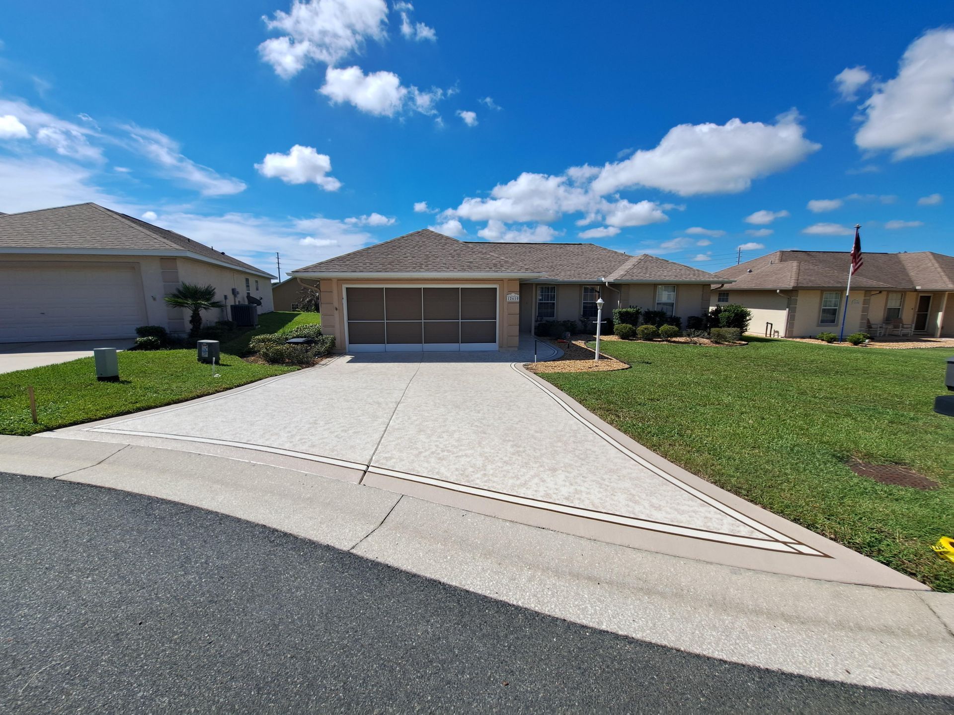 A house with a large driveway and a lawn in front of it