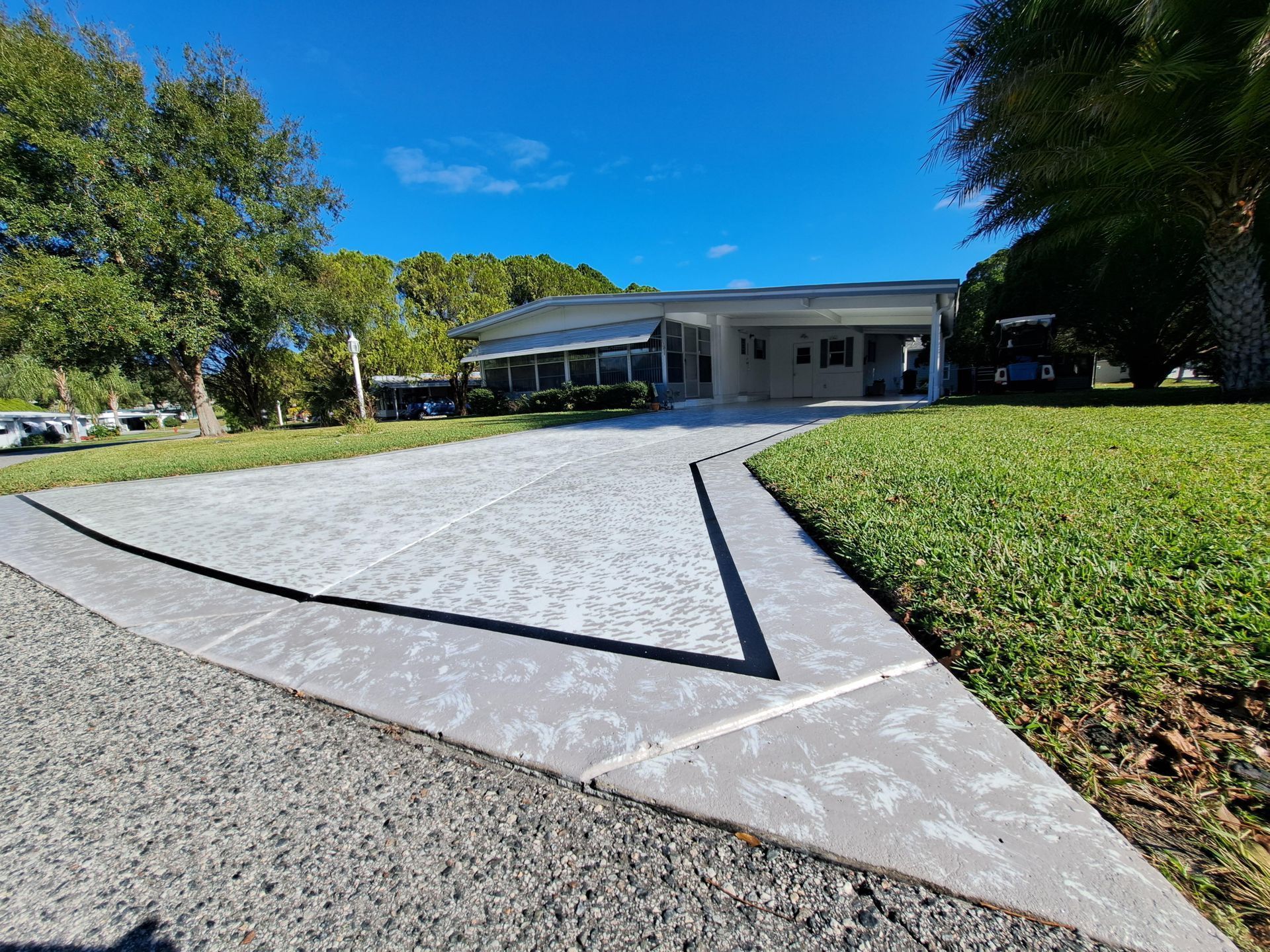 A concrete driveway leading to a house on a sunny day.
