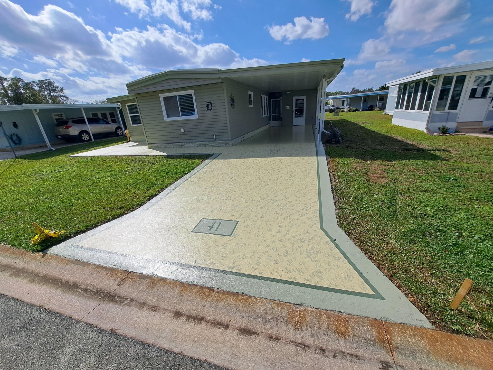 A mobile home with a driveway and a car parked in front of it.
