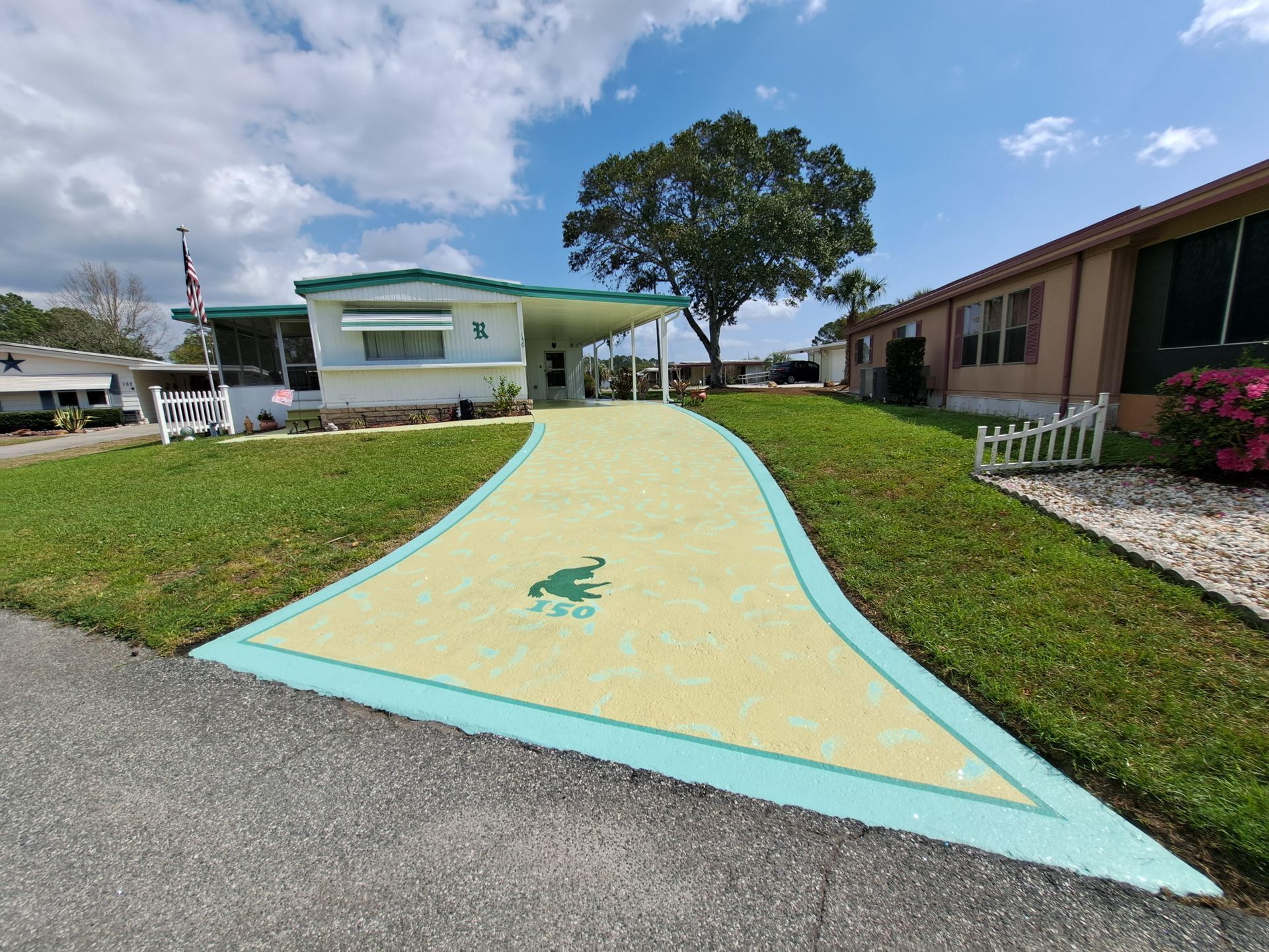A frog is painted on the sidewalk in front of a mobile home.