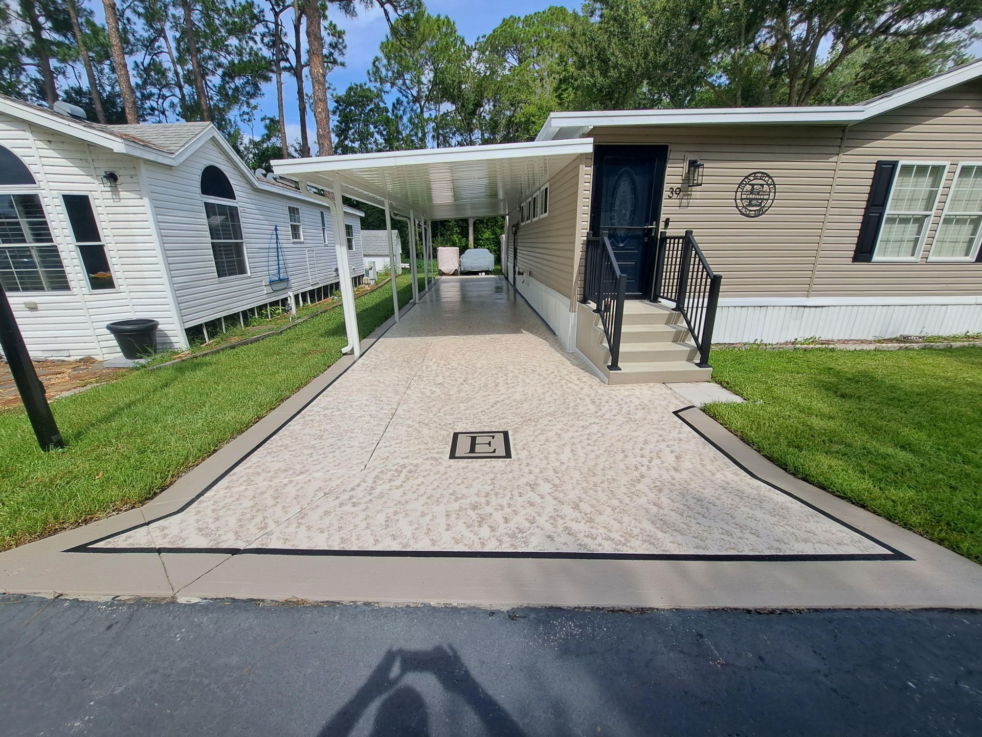 A driveway leading to a mobile home with a canopy over it.