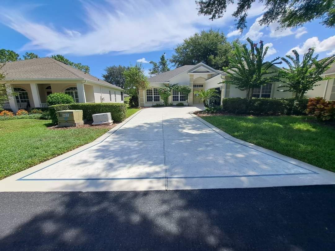 A concrete driveway leading to a large white house.